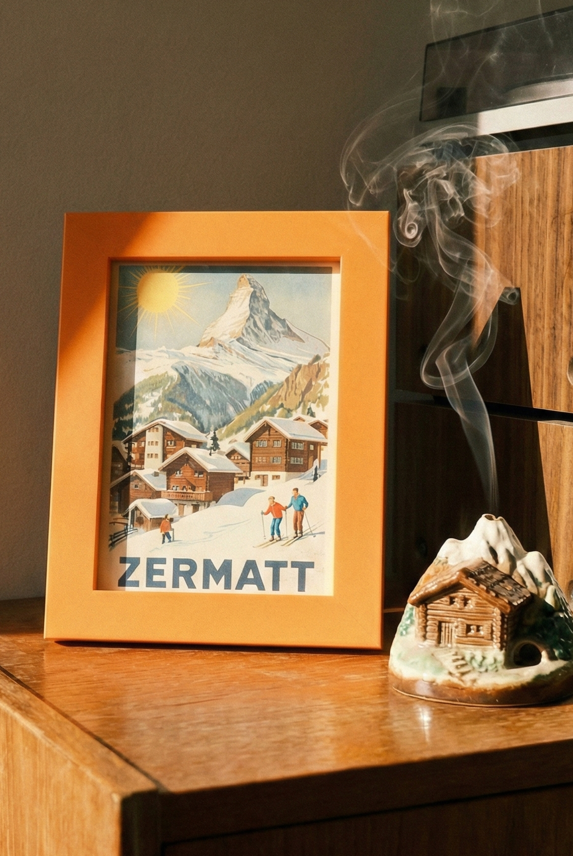 Wooden cabinet with a framed picture of Zermatt, a smoking incense burner, and a vintage radio.