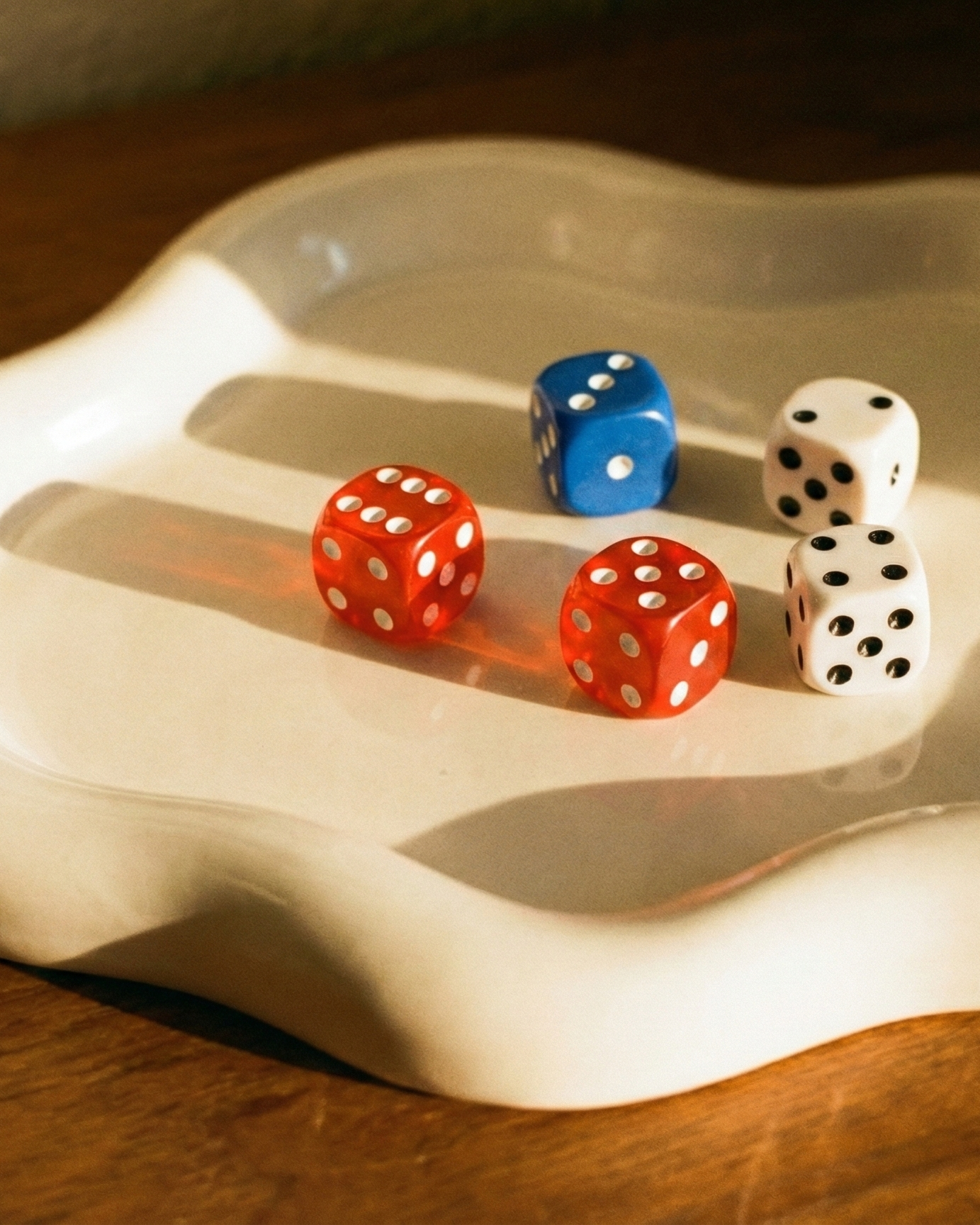 Five dice in different colors on a wavy ceramic surface