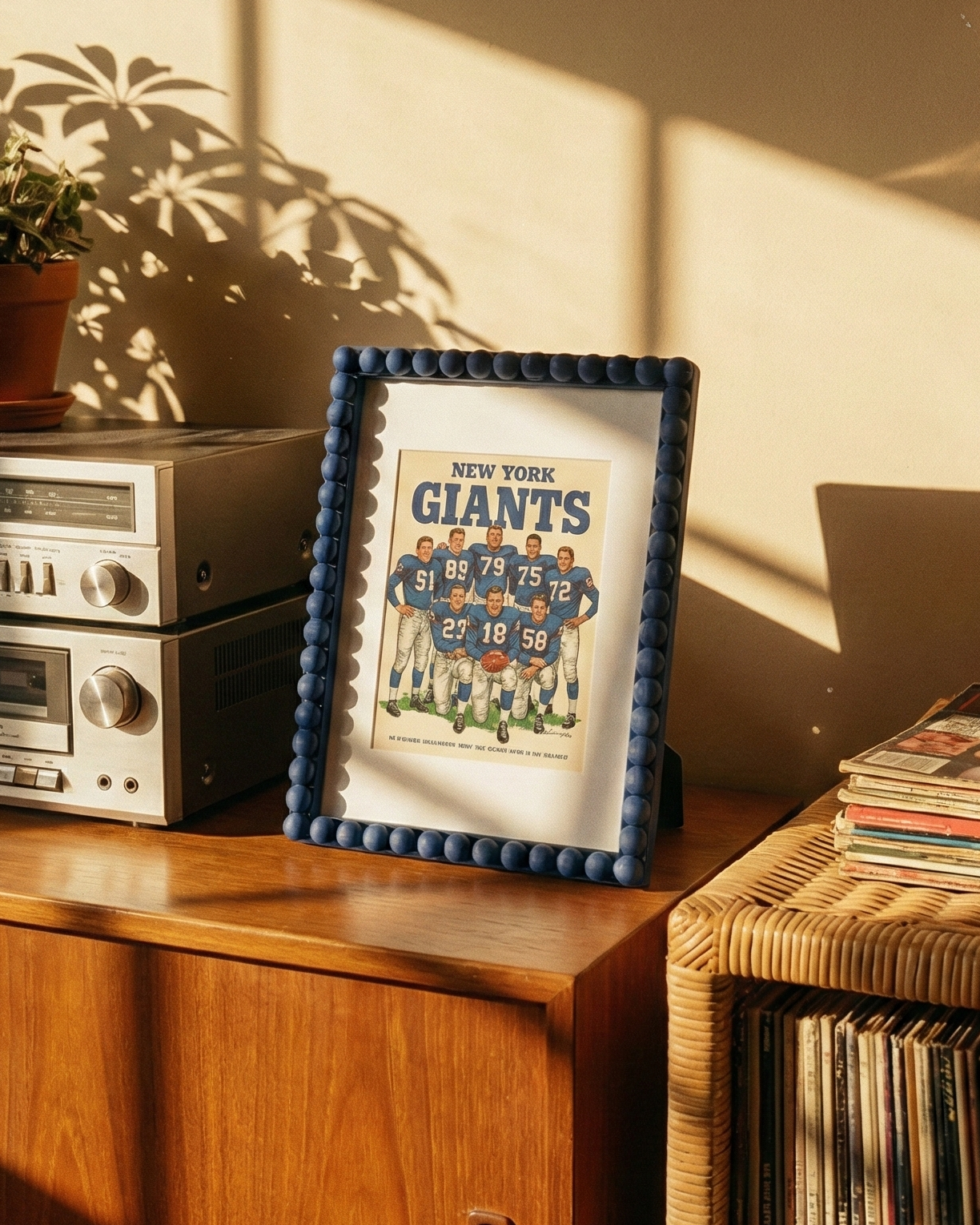 Vintage stereo system with a framed New York Giants poster on a wooden shelf.
