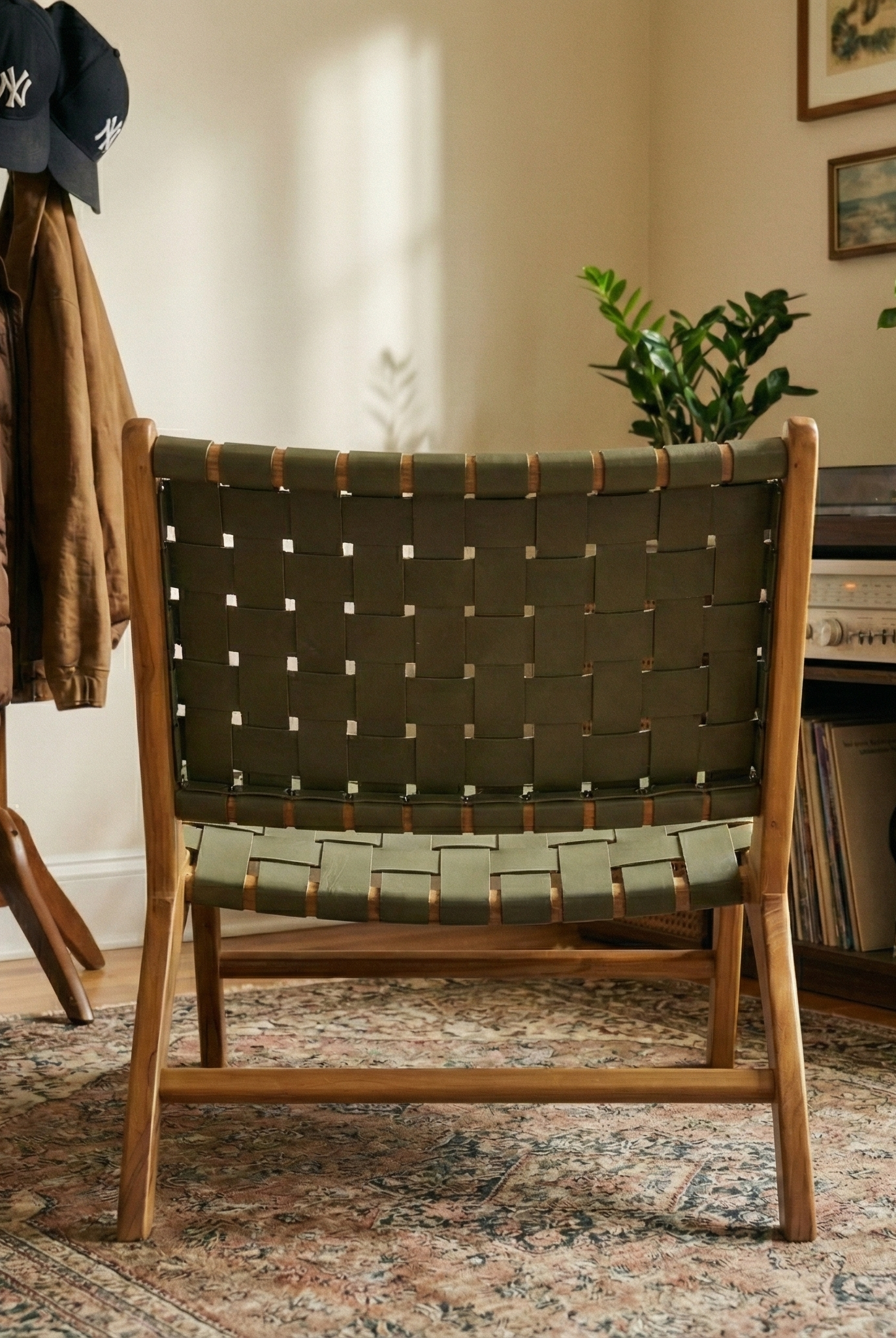 Chair with woven backrest in a room with a coat rack and plants