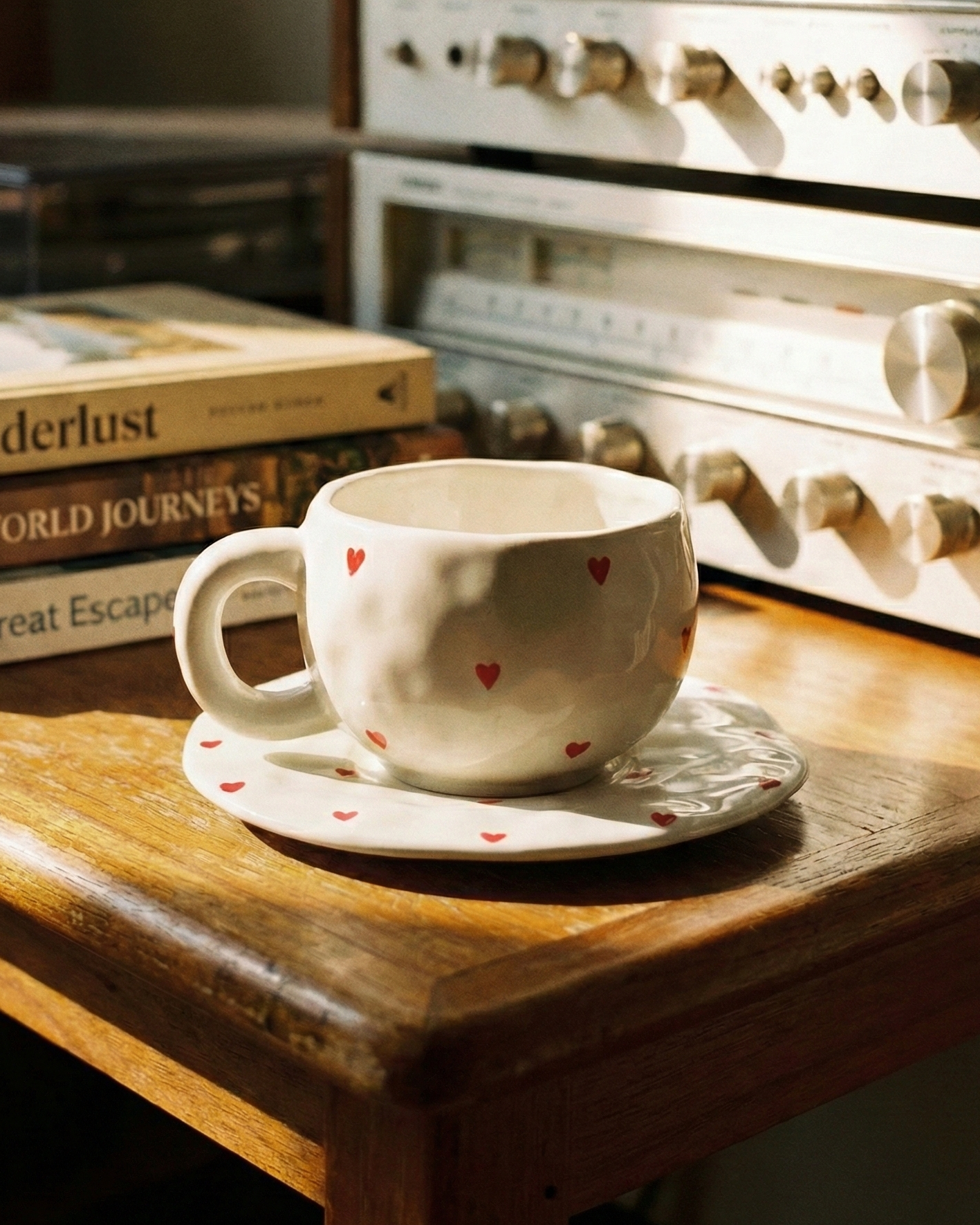 Ceramic cup with heart design on a saucer in front of vintage stereo equipment.