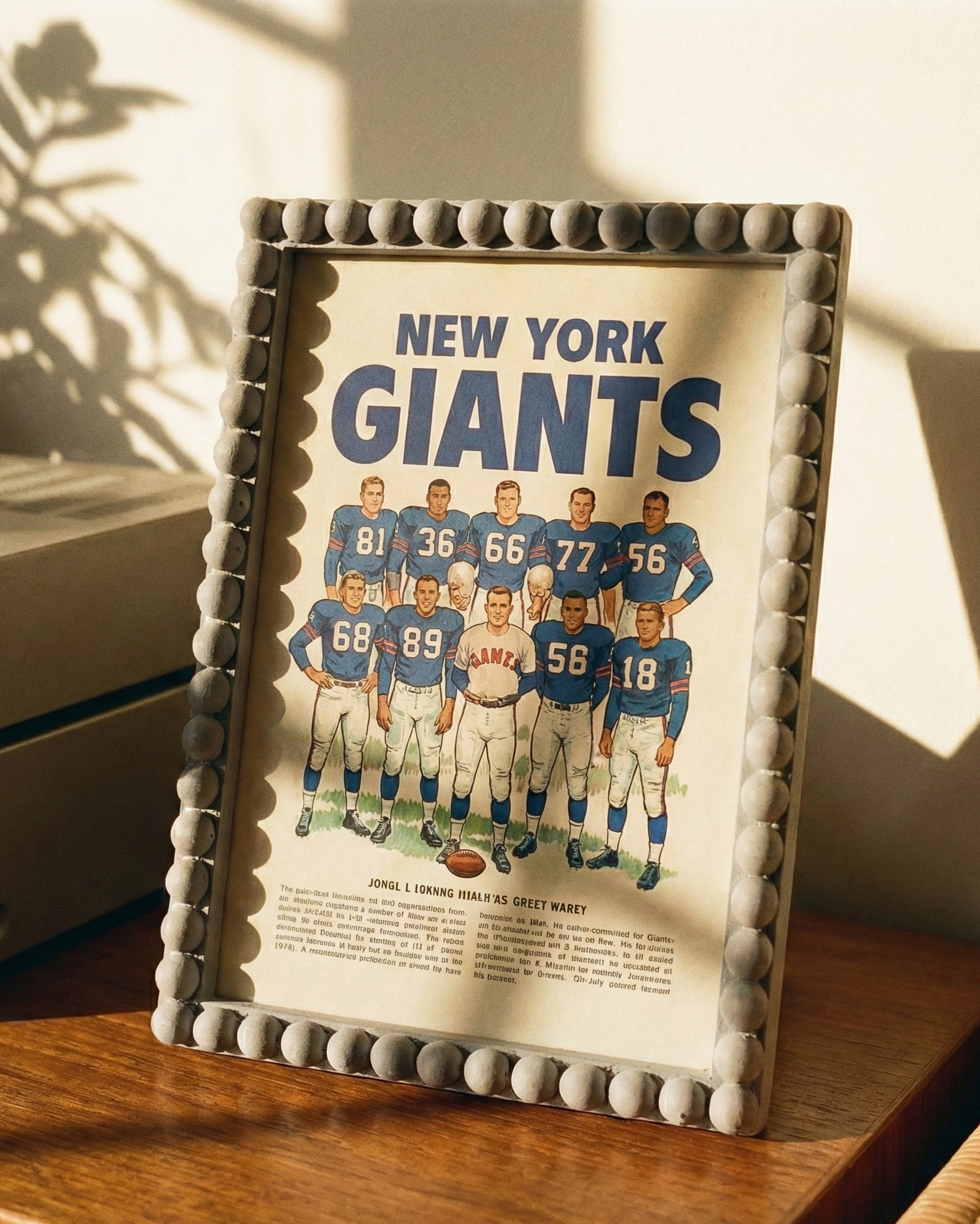 Framed New York Giants poster on a wooden surface with sunlight casting shadows.