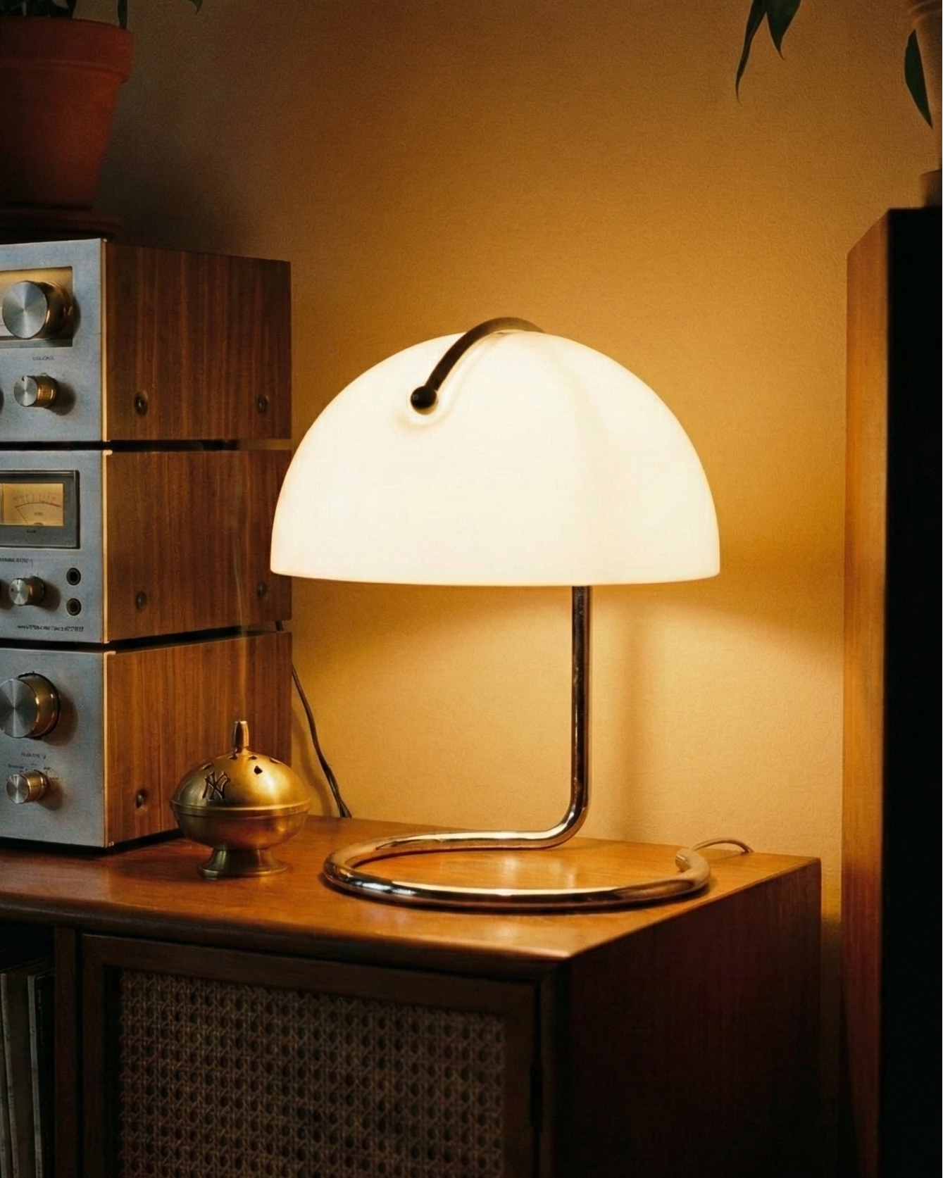 Vintage stereo equipment with a lamp on a wooden surface in a warm, dimly lit room.