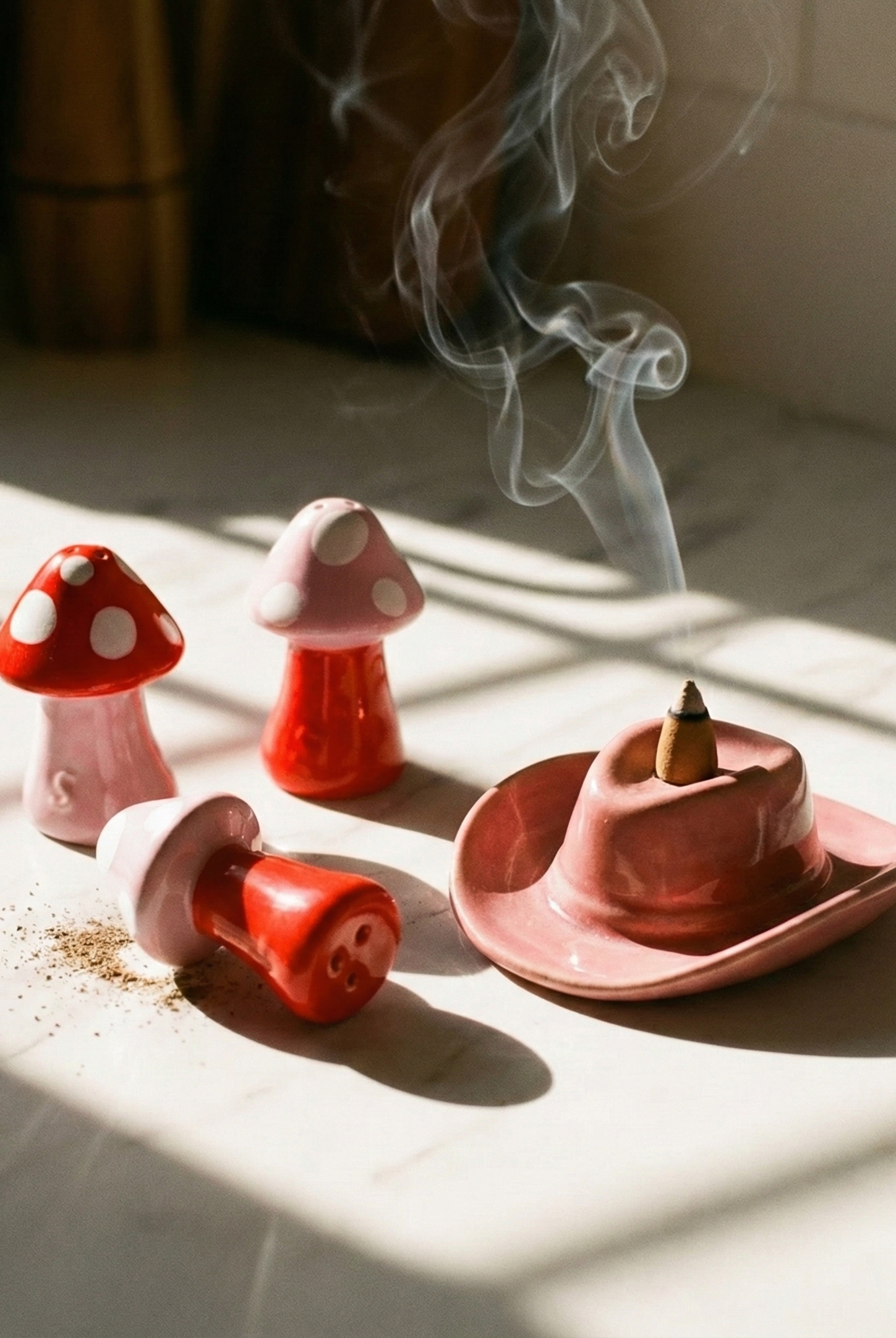 Set of mushroom-shaped incense burners with smoke on a marble surface.