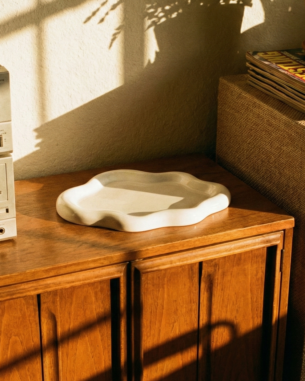 Vintage stereo system on a wooden cabinet with vinyl records and plants in the background