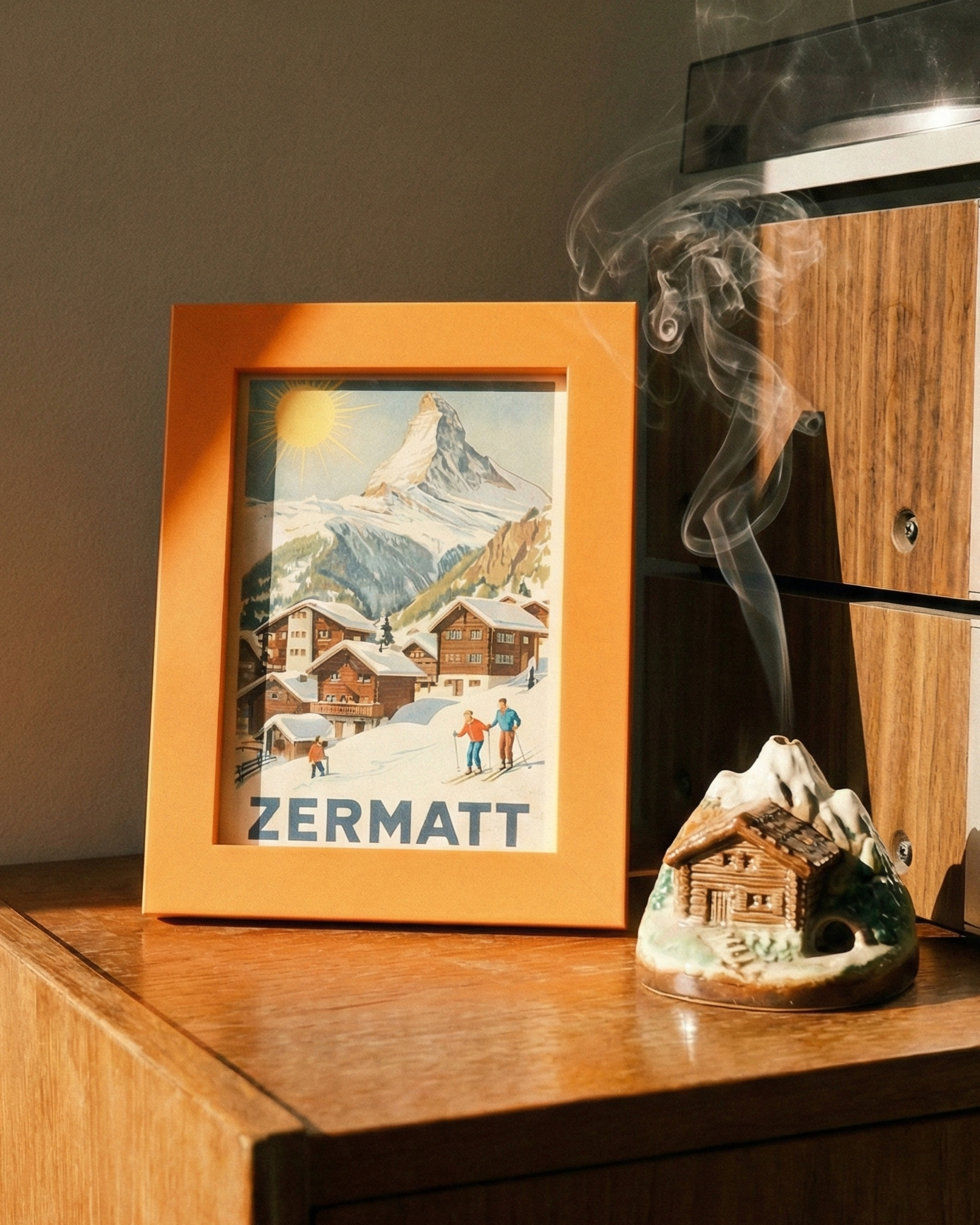 Wooden cabinet with a framed picture of Zermatt, a smoking incense burner, and a vintage radio.