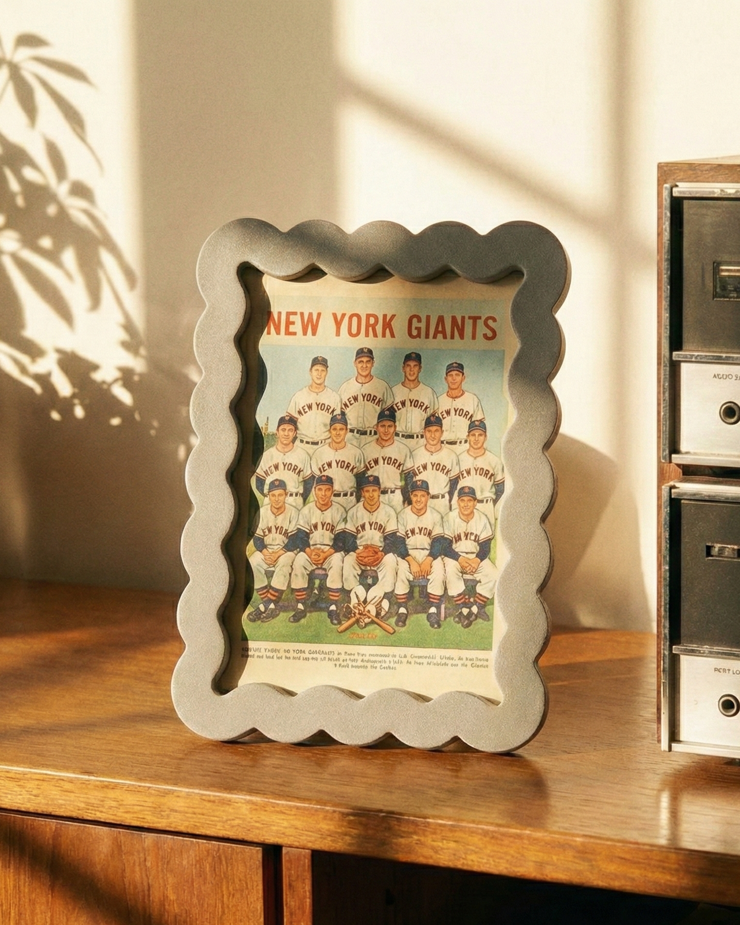 Framed New York Giants poster on a wooden surface with vintage radio and magazines.