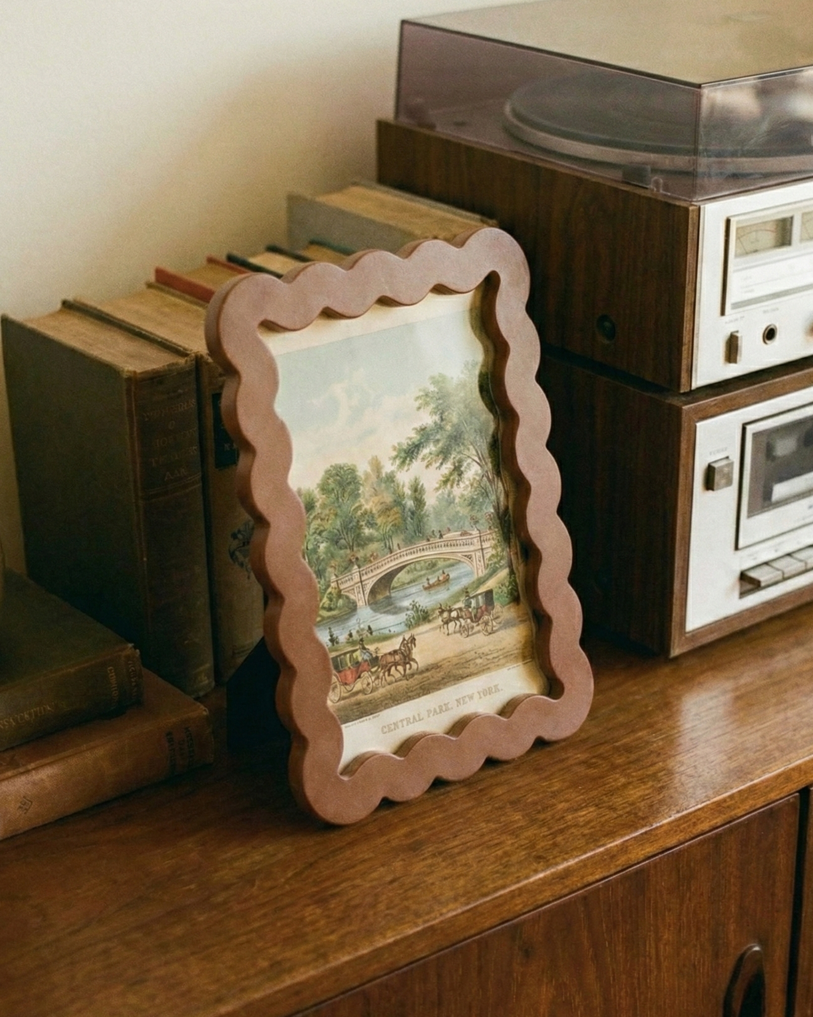 Vintage record player with books and a framed picture on a wooden surface.