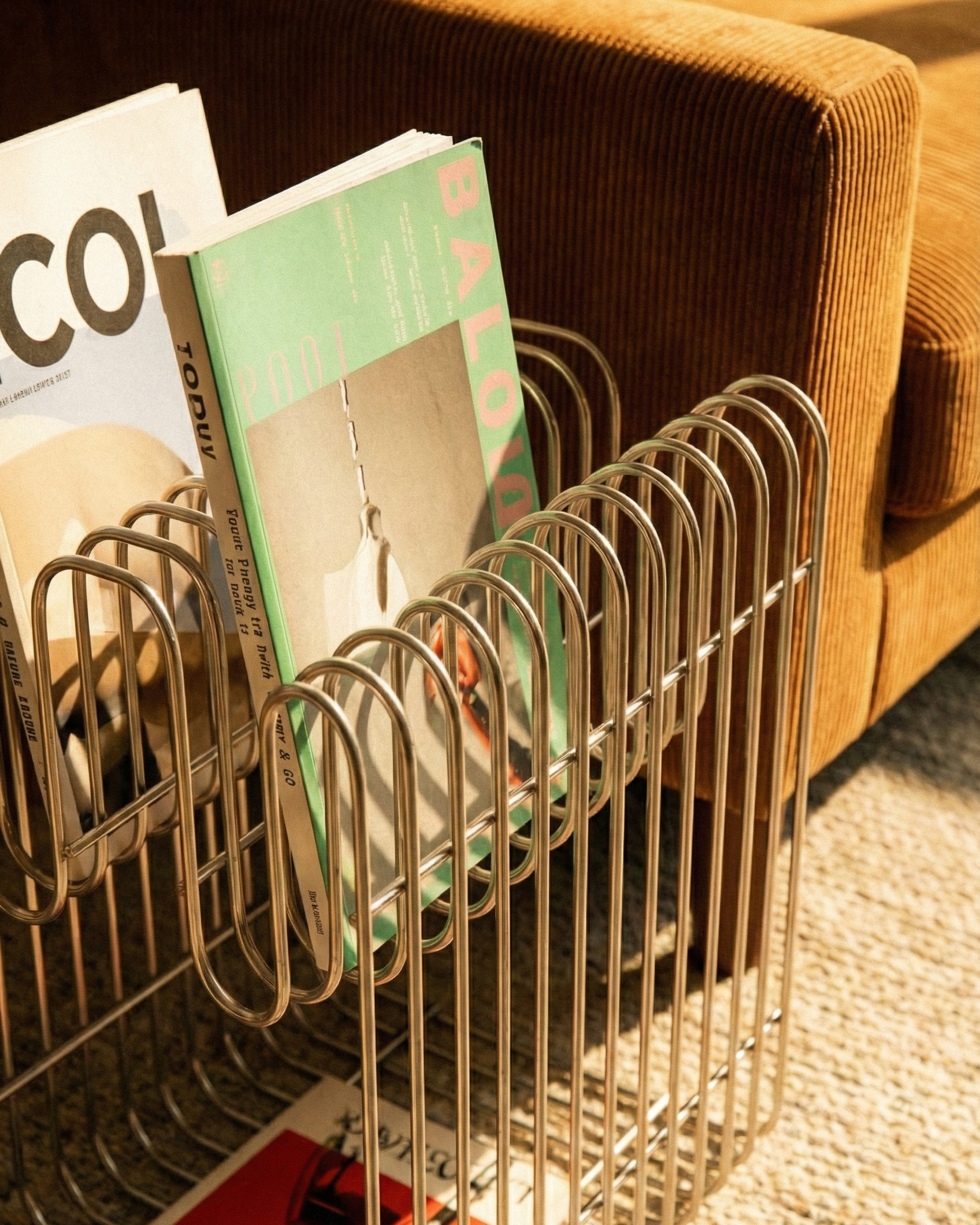 Metal magazine rack with books on a brown couch