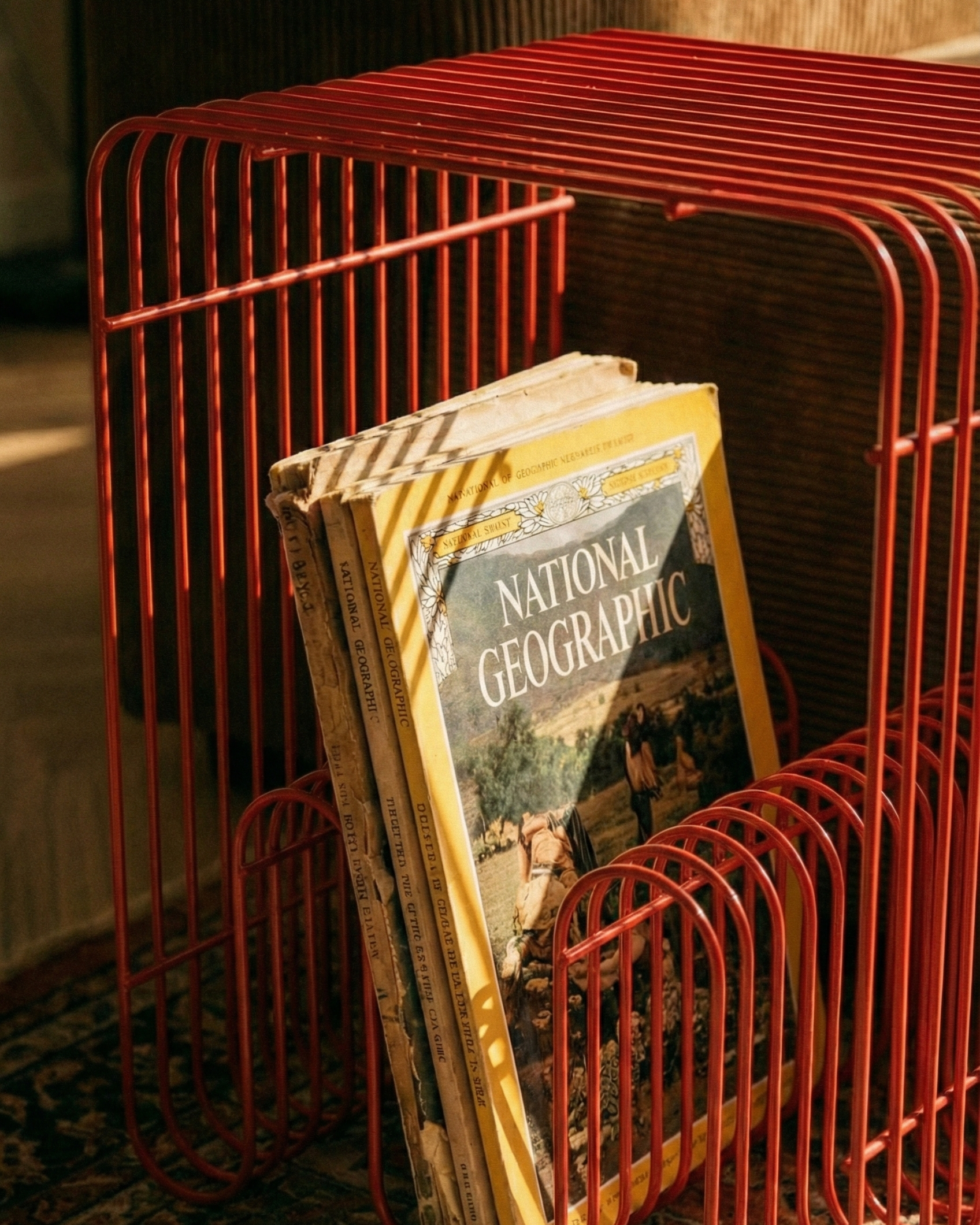 Red wire magazine holder with National Geographic books inside