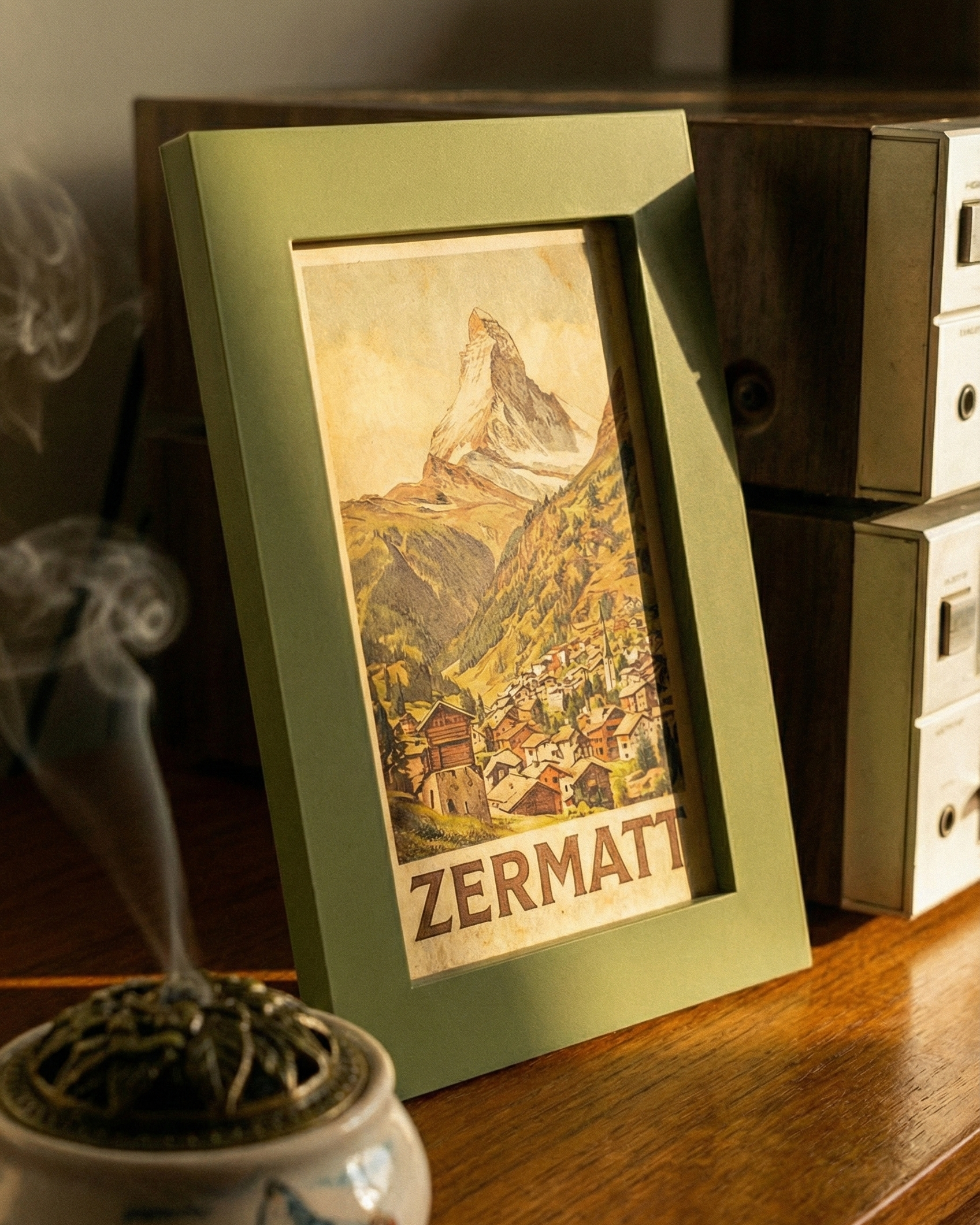 Framed picture of Zermatt with a smoking incense burner on a wooden surface