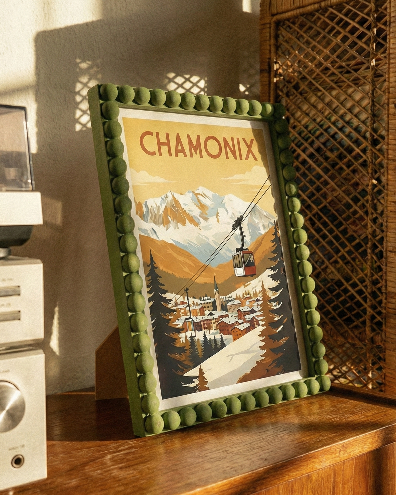 Framed artwork of Chamonix with a mountain and cable car scene on a wooden surface.