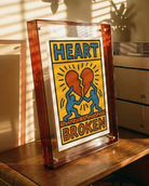 Framed artwork with 'Heart Broken' design on a wooden surface.