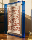 Decorative plaque with 'Switzerland St. Moritz '96' design on a wooden surface.
