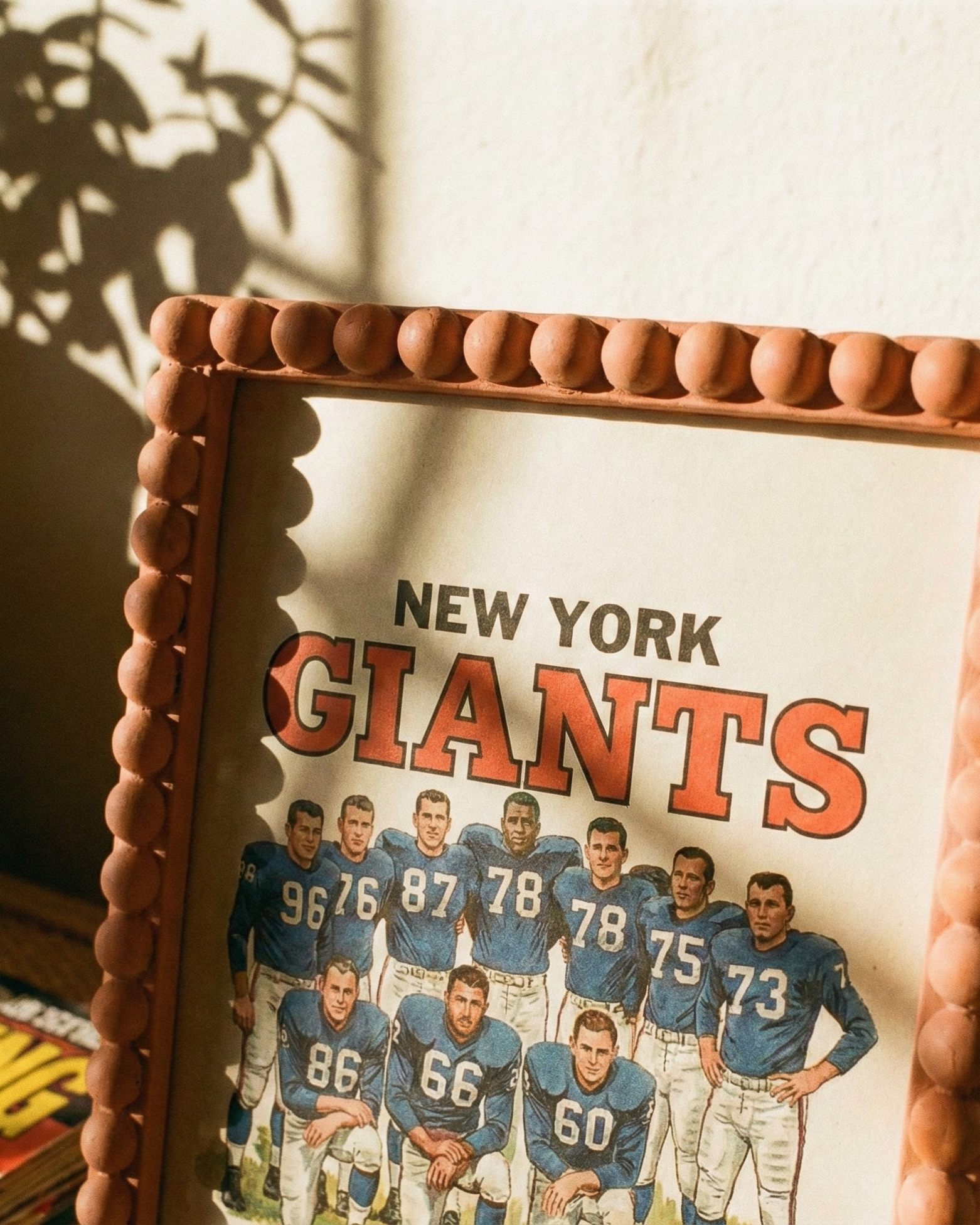 Framed poster of New York Giants football team on a table with sunlight casting shadows.