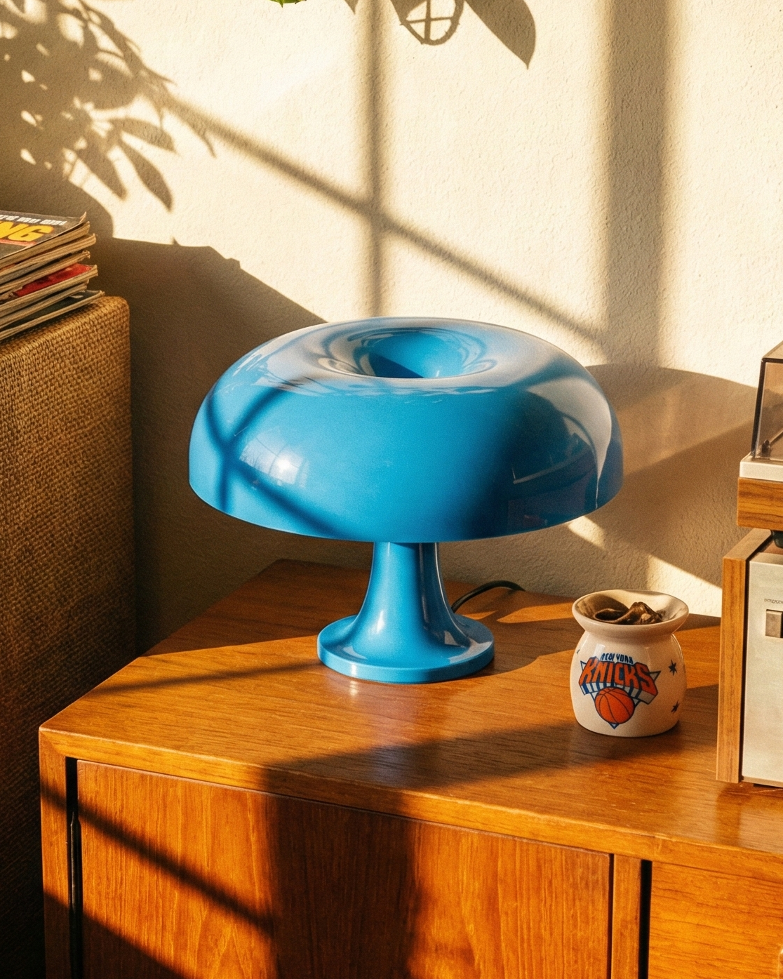 Vintage record player on a wooden cabinet with a blue lamp and vinyl records.